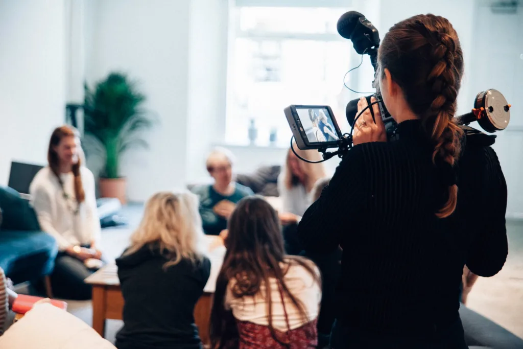 A cameraman documenting people having a group discussion