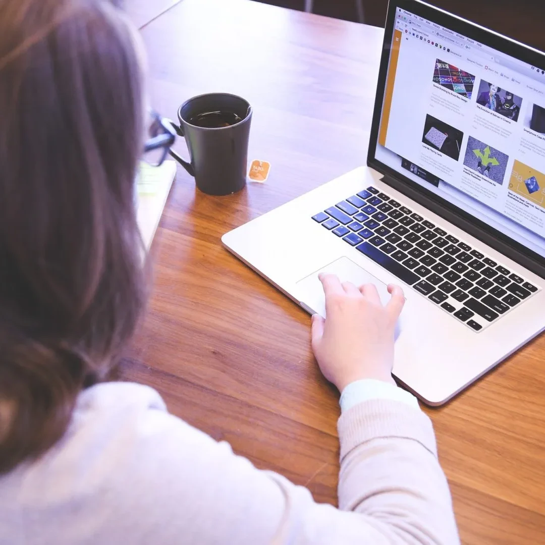 A woman with black hair working on a laptop