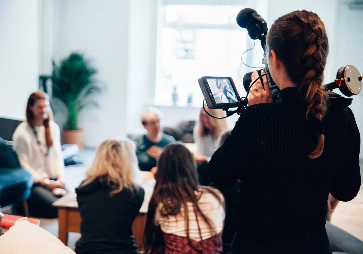 A cameraman documenting people having a group discussion