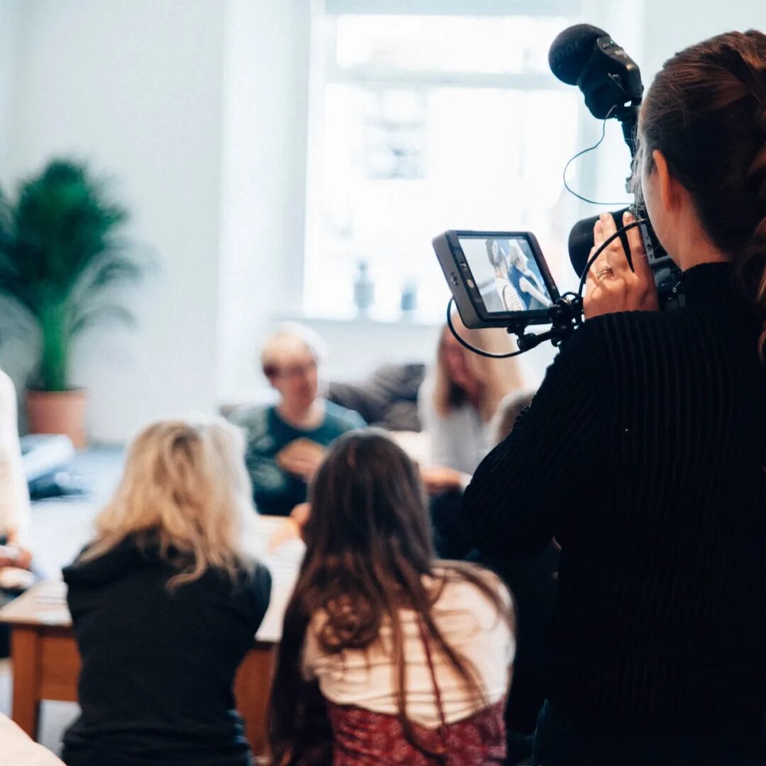 A cameraman documenting people having a group discussion